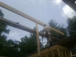 Carpenter setting a ridge beam over a new addition frame — Ice Dam Removal by Roofing Brothers in Oneco