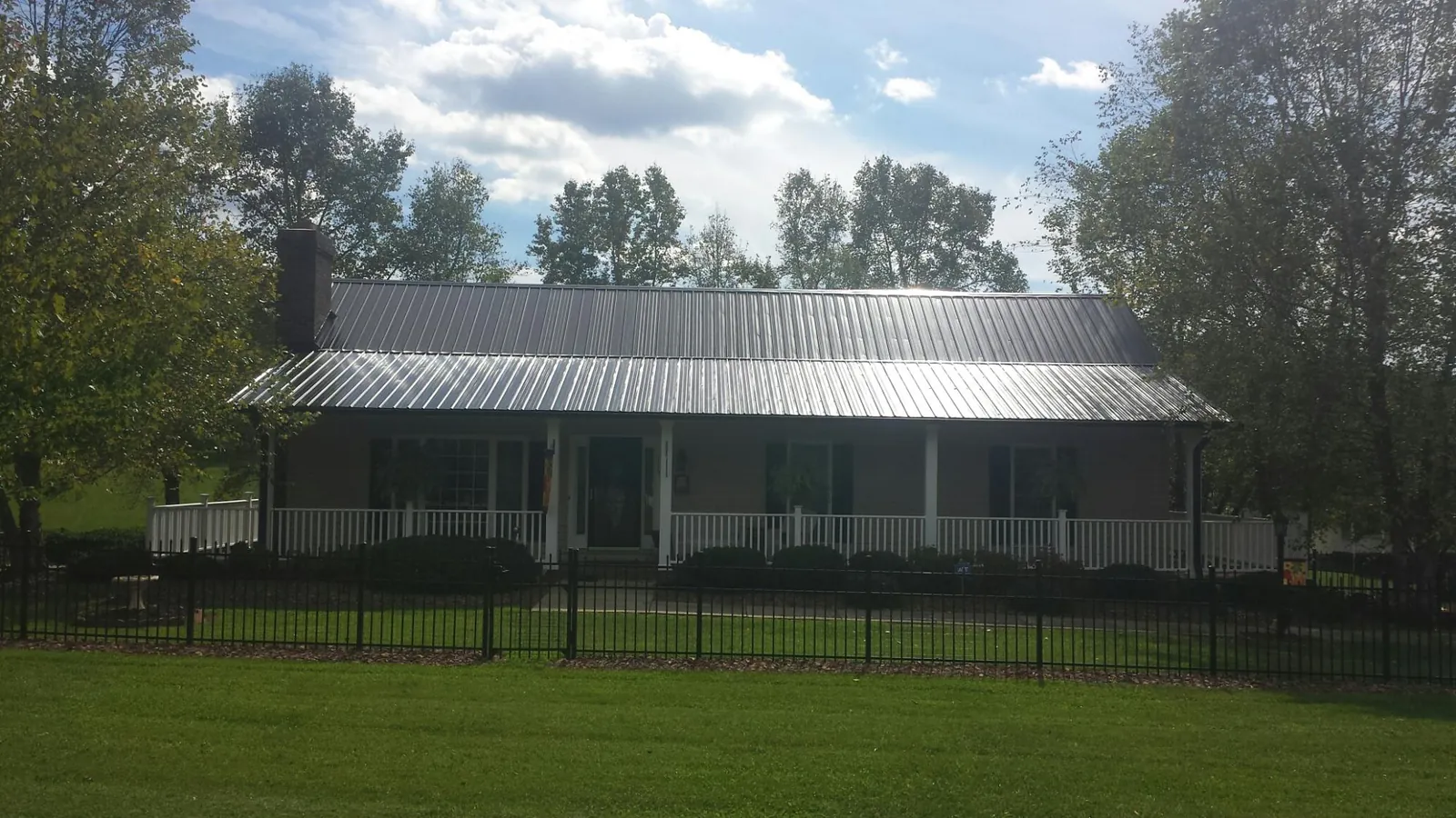 Gray metal roof on a brick ranch with a full width front porch — Gutter Guard Installation work by our crew in Oneco