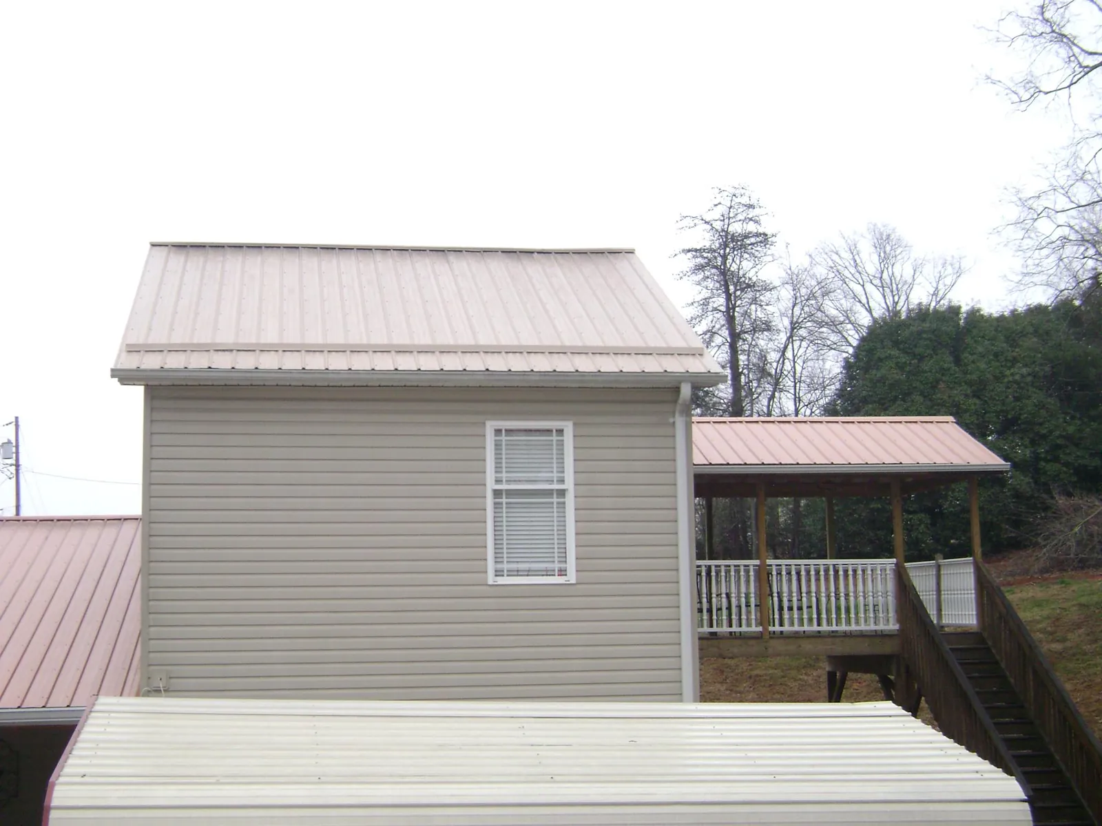 Tan metal roofs on a two story addition and attached porch, from a Roof Replacement job in Oneco